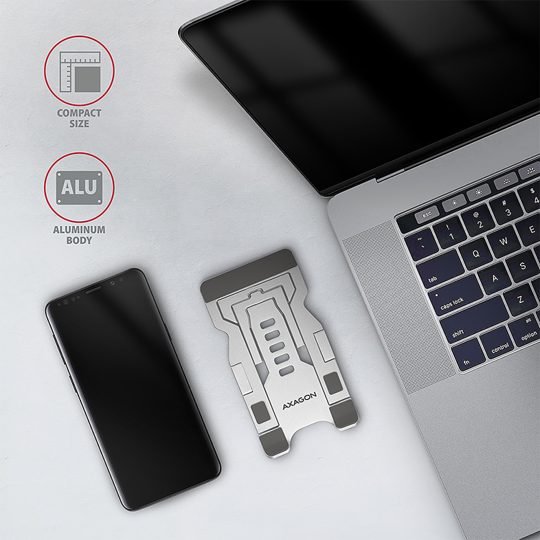 Laptop ezüst állvánnyal és okostelefonnal fehér felületen.