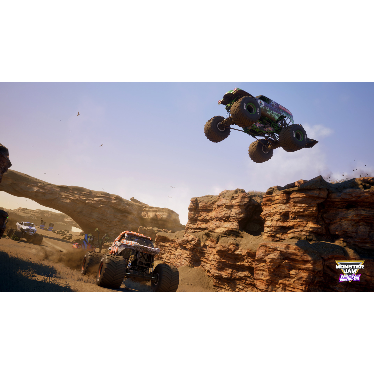 Monster Jam trucks springen op een zandbaan onder een blauwe hemel. Grave Digger is in de lucht.