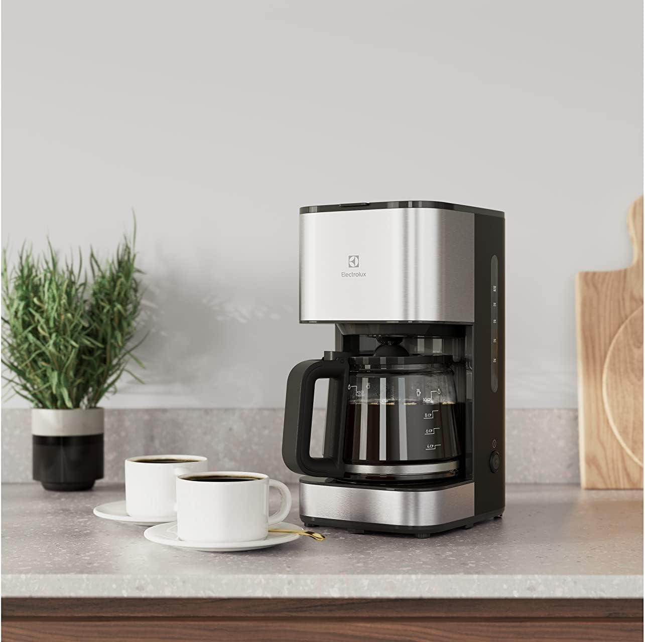 Ekspres do kawy z dwoma białymi filiżankami na stole.