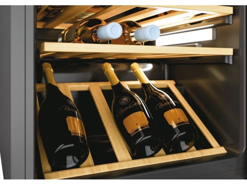 Réfrigérateur à vin avec plusieurs bouteilles à l'intérieur, certaines couchées, d'autres debout.
