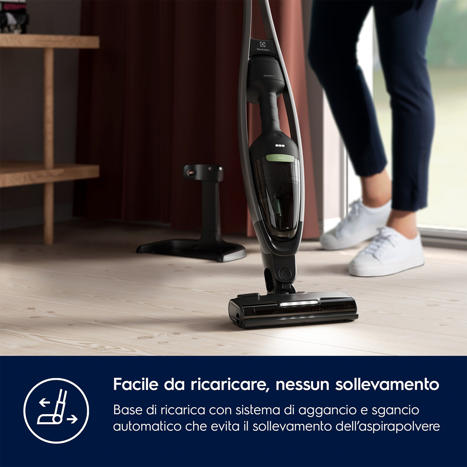 Aspirapolvere nero con una persona sullo sfondo. L'aspirapolvere è su pavimento in legno.