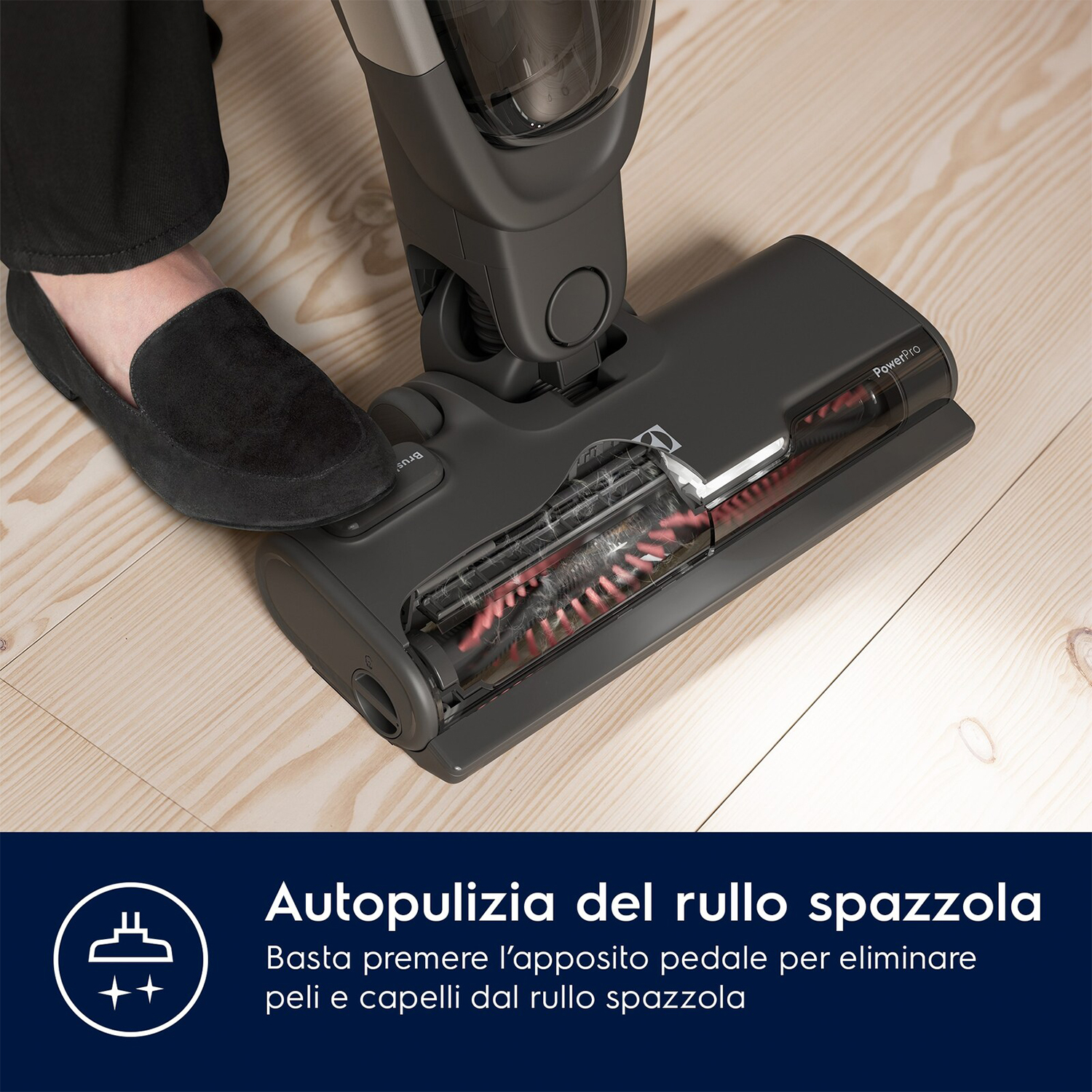 Primo piano di una testina per aspirapolvere con setole. Un piede calpesta il pavimento.