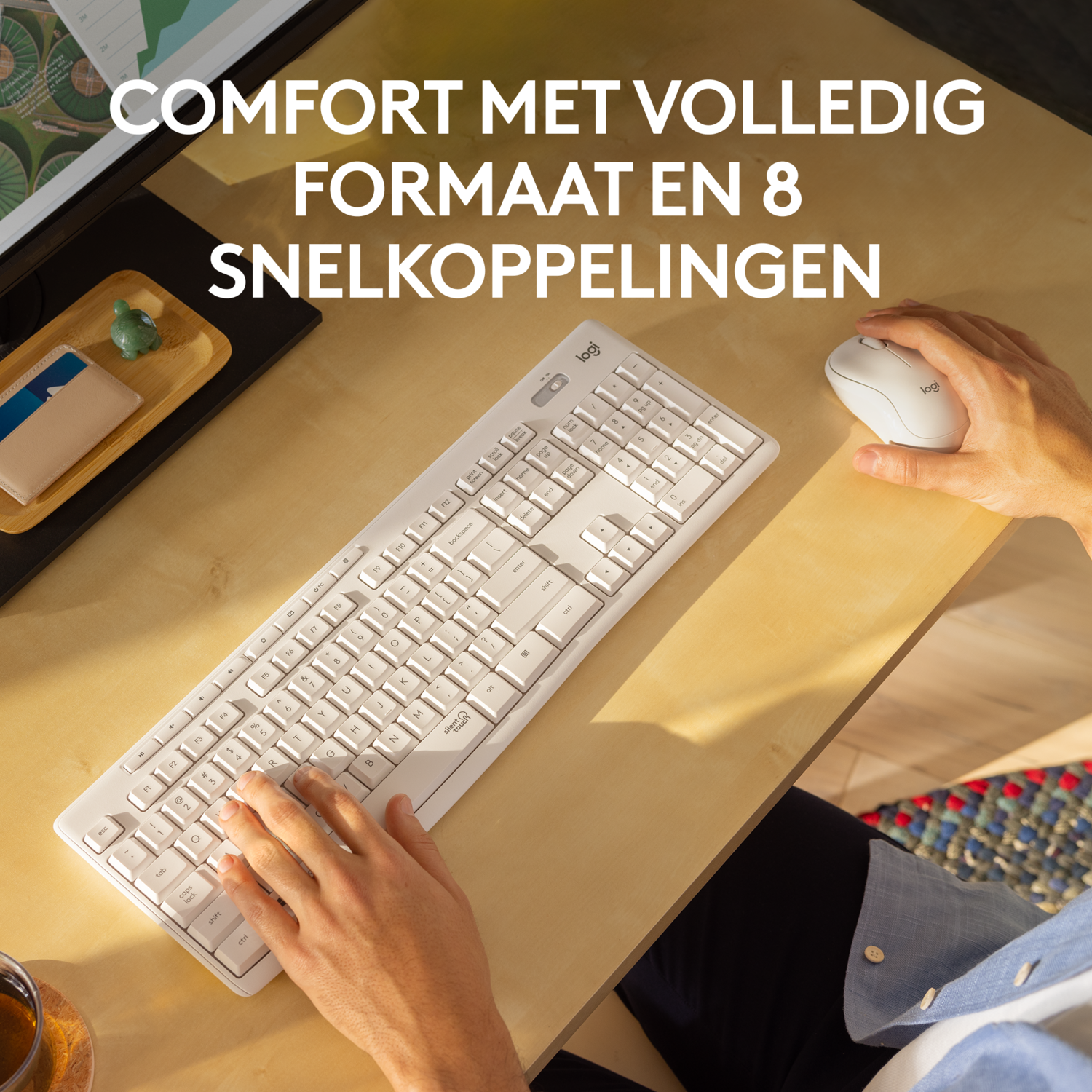Persoon die een wit toetsenbord en muis gebruikt op een lichte houten bureau.