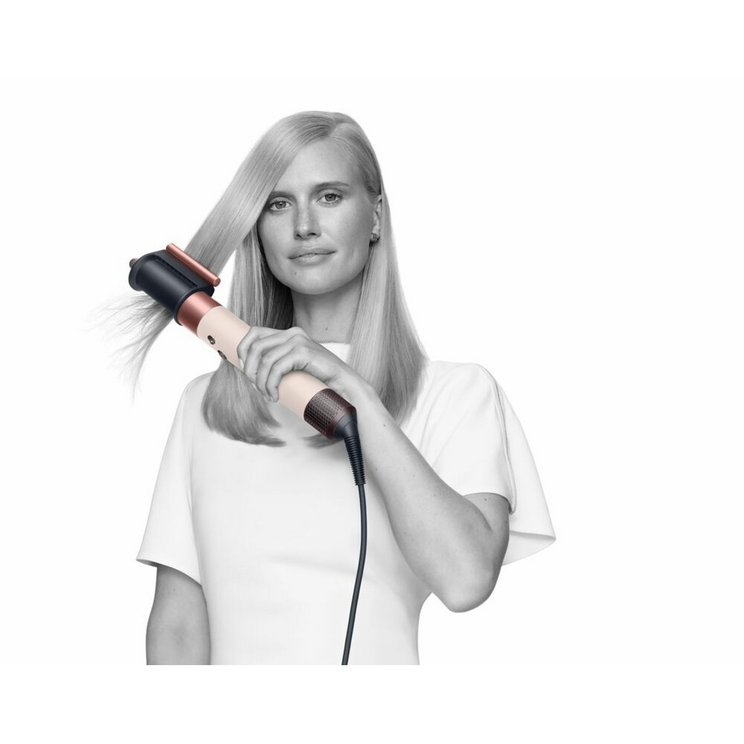 Femme utilisant un styler capillaire noir et or rose. Elle le tient sur ses cheveux, regardant la caméra.