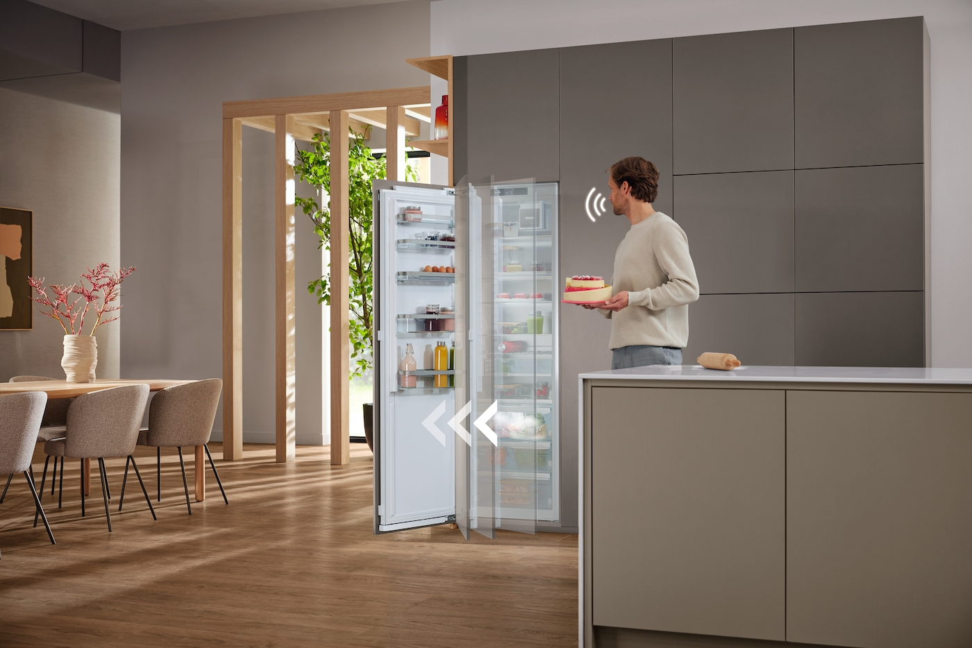 Mann hält Kuchen vor offenem Kühlschrank mit Innenbeleuchtung.