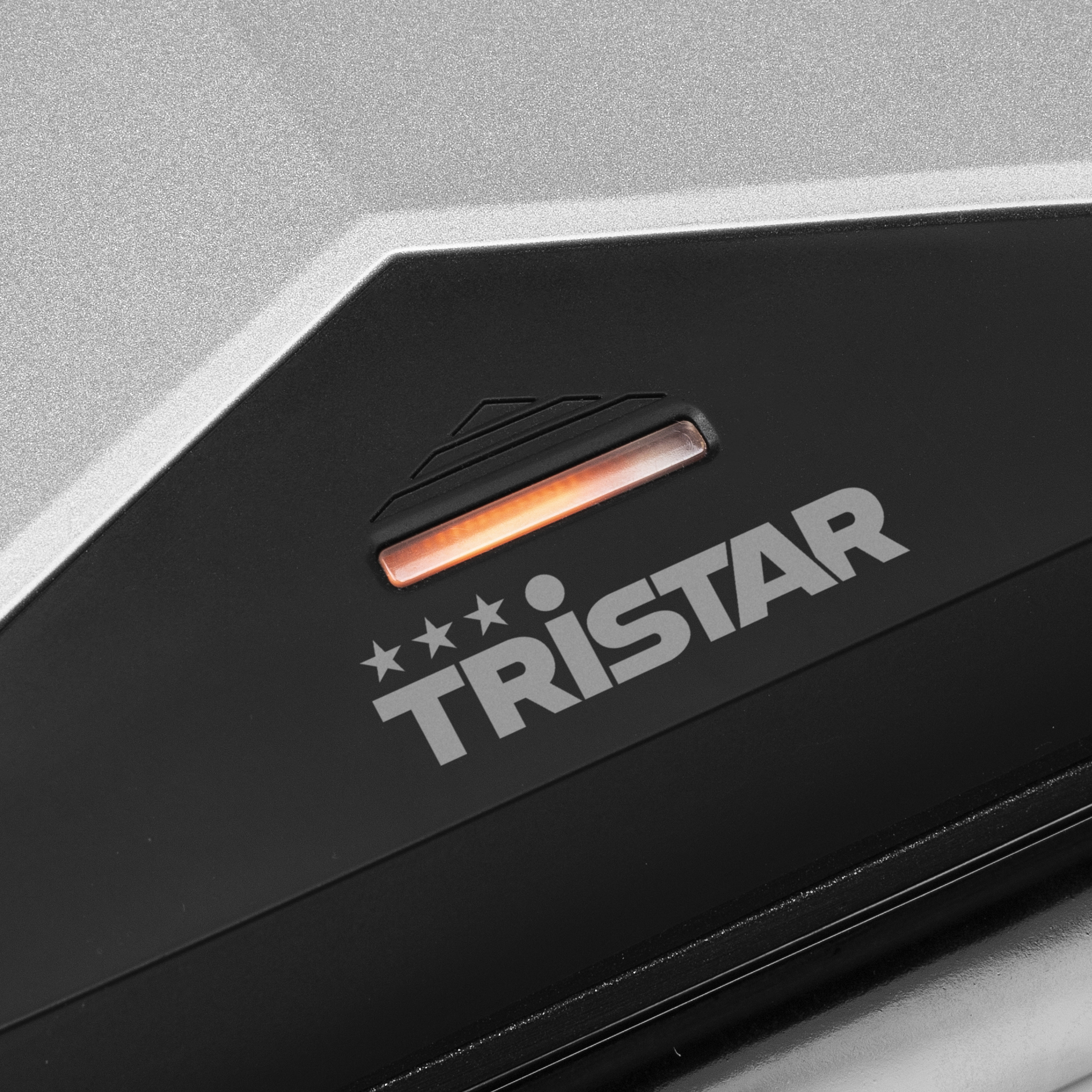 Nahaufnahme eines schwarzen Geräts mit dem Tristar-Logo und einem leuchtenden orangen Licht.