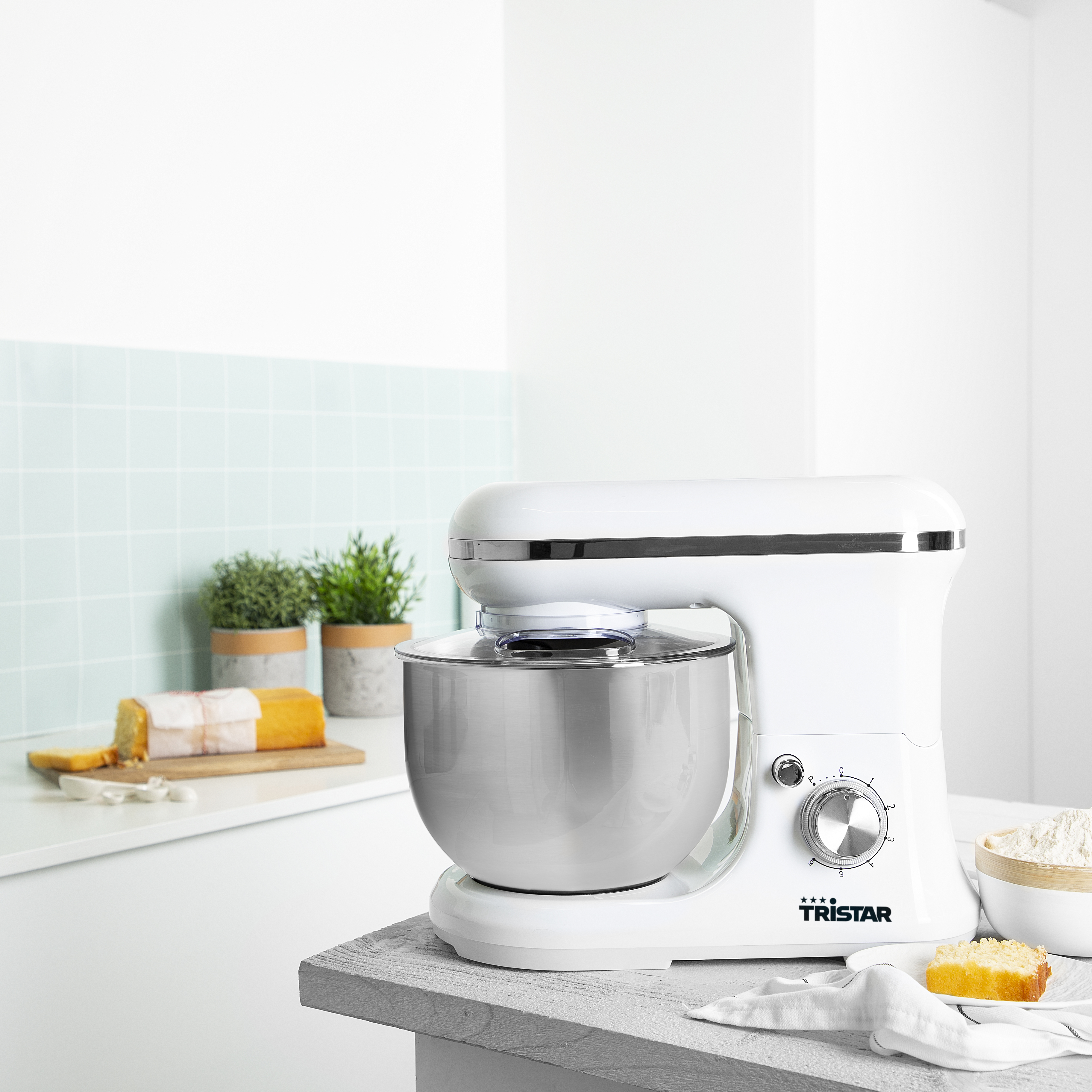 Robot culinaire blanc avec un bol en acier inoxydable sur une table blanche.