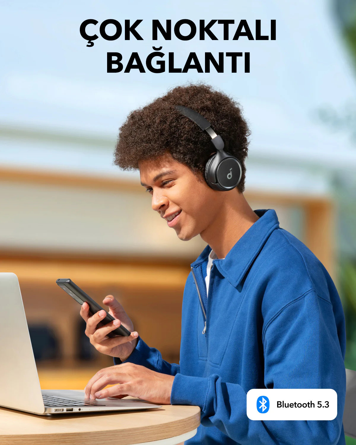 Kulaklık takan adam, telefon ve laptop kullanıyor. Bluetooth 5.3. Üstte Çok Noktalı Bağlantı yazısı.