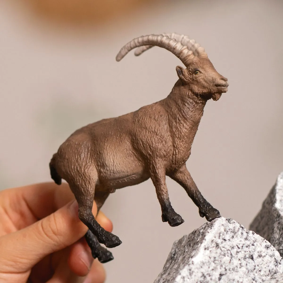 Eine Figur einer braunen Ziege, die sich an Felsen festhält.