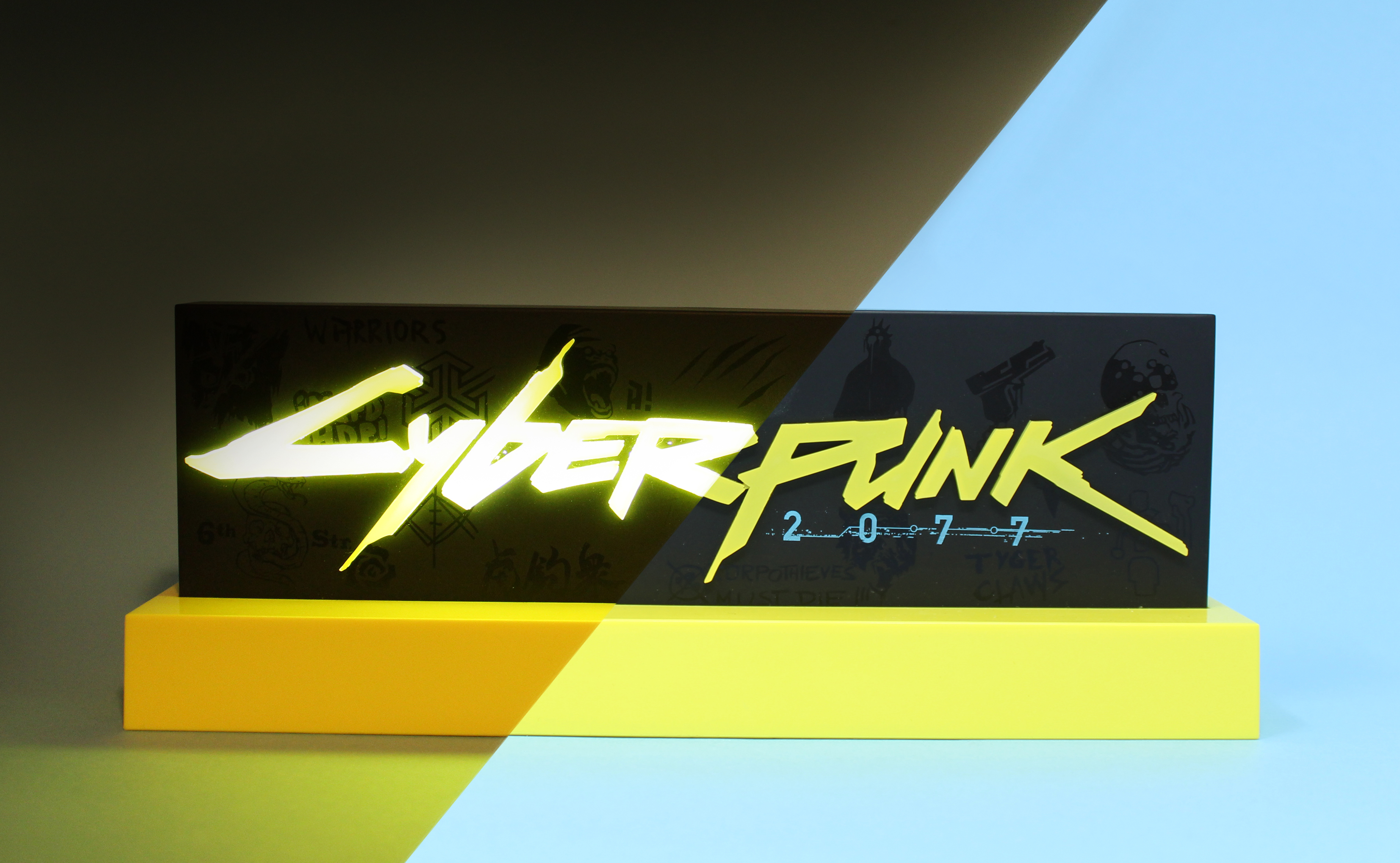 Ein schwarz-gelbes 'Cyberpunk 2077'-Display auf einer gelben Plattform, mit blauem und schwarzem Hintergrund.