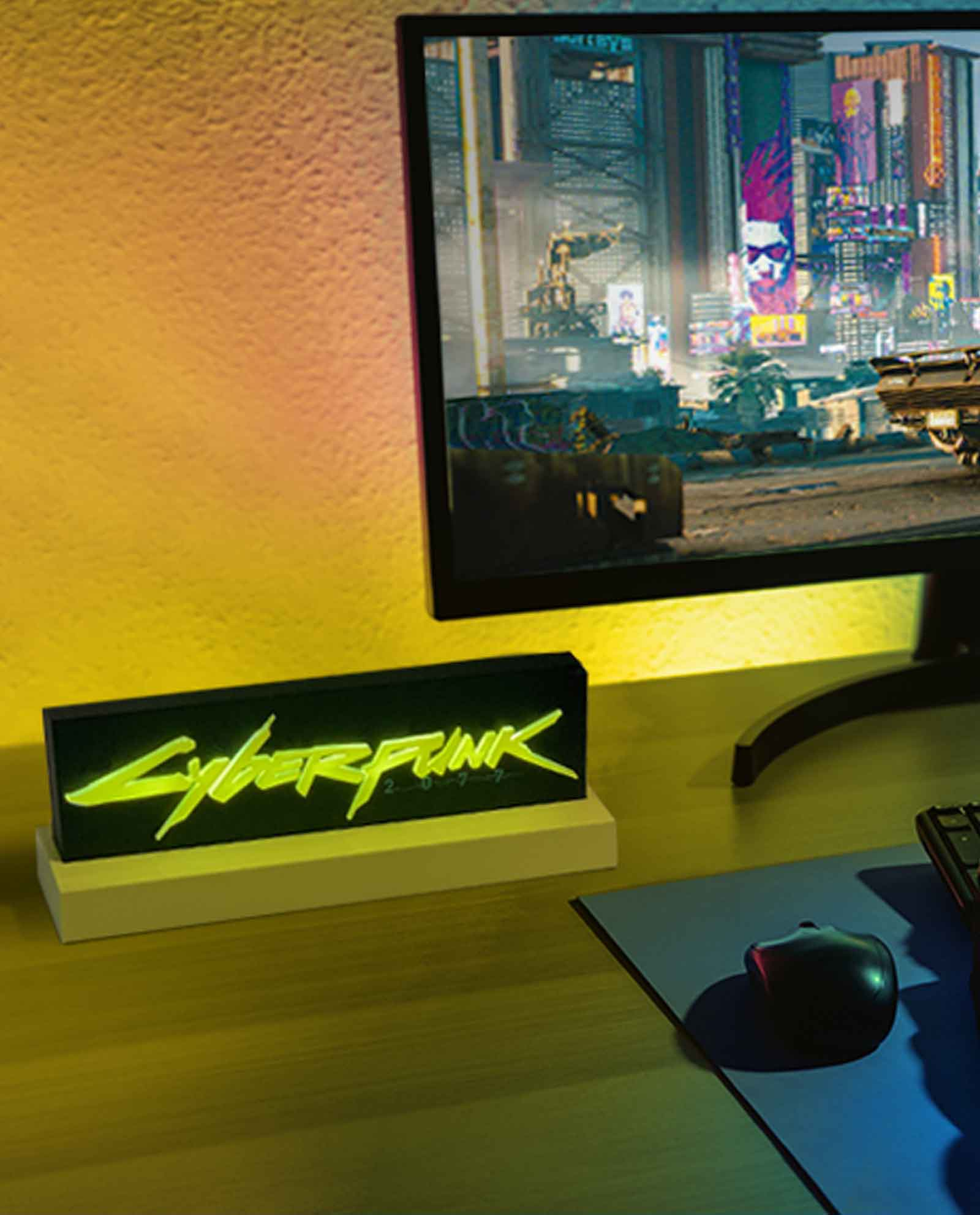 Ein beleuchtetes Neon-Cyberpunk-Schild auf einem Schreibtisch vor einem Computerbildschirm.