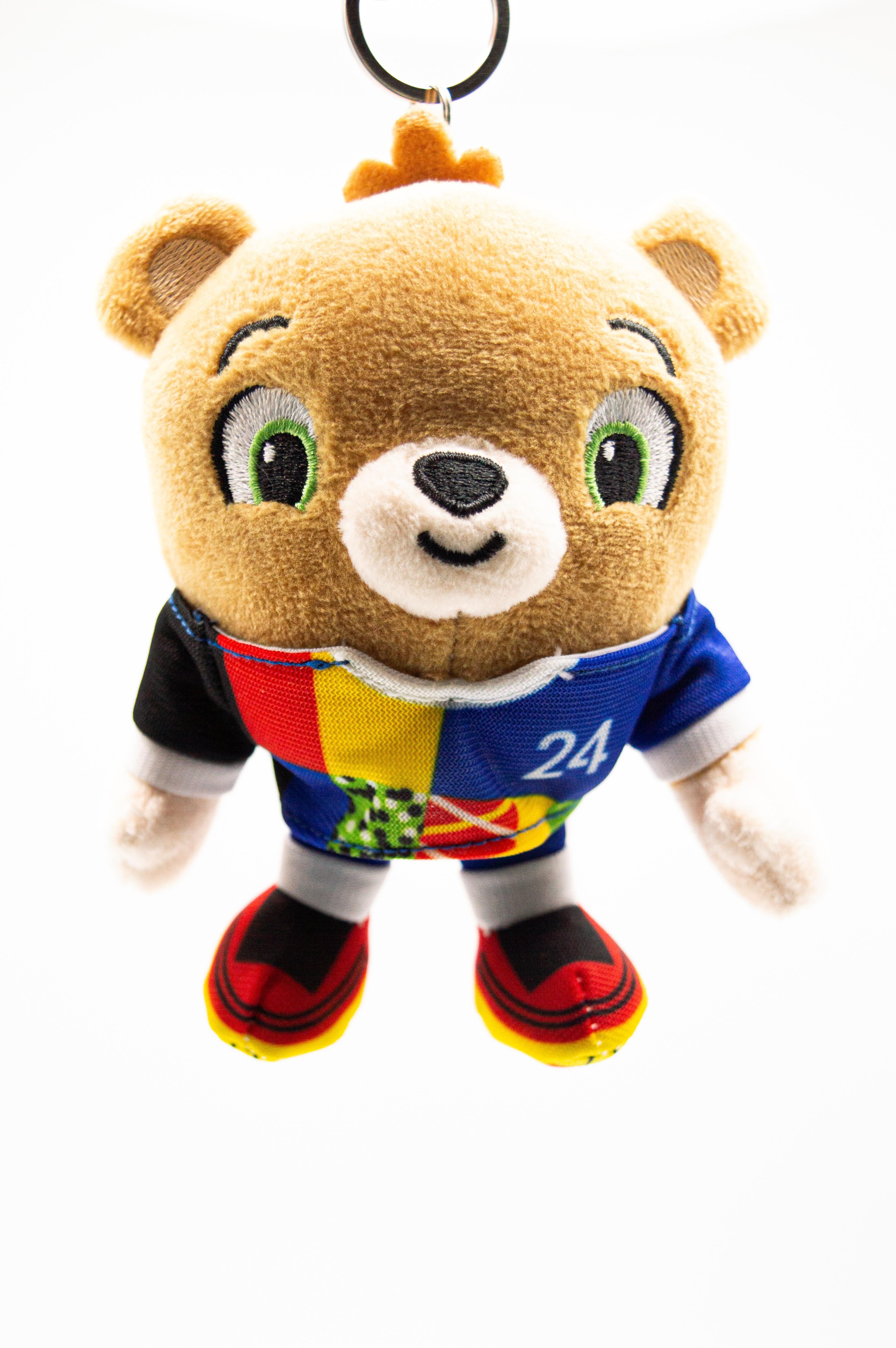 Brauner Teddybär mit blauem Trikot und buntem Design. Weißer Hintergrund.
