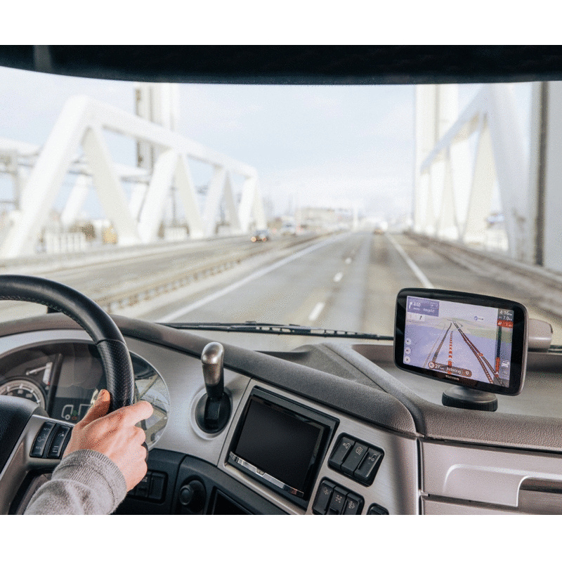 Manos del conductor en el volante y un dispositivo GPS en el salpicadero. Se ve un puente.
