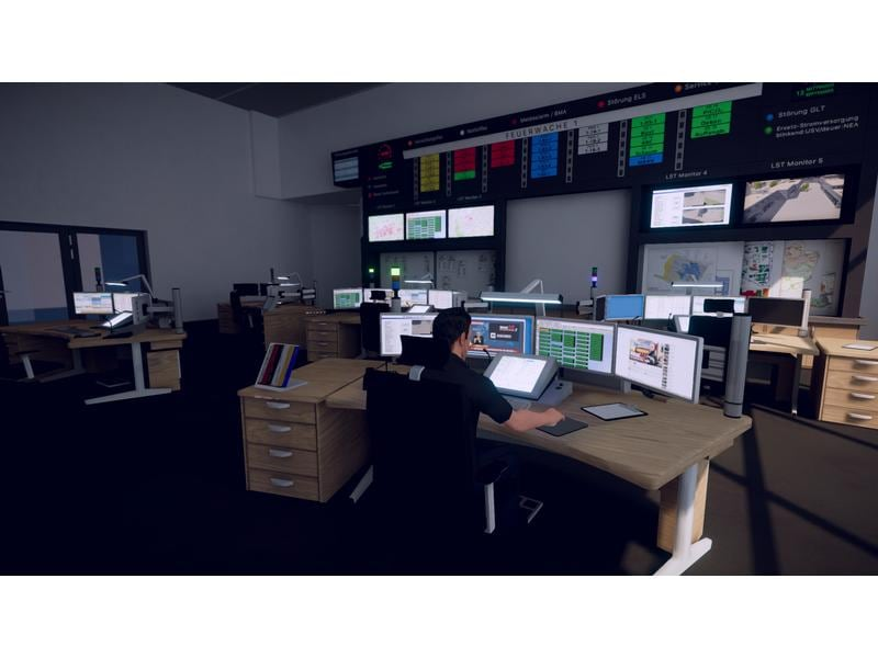 Ein Mann sitzt in einem Kontrollraum an einem Schreibtisch, umgeben von Computern und Monitoren. Informationsanzeigen an der Wand.