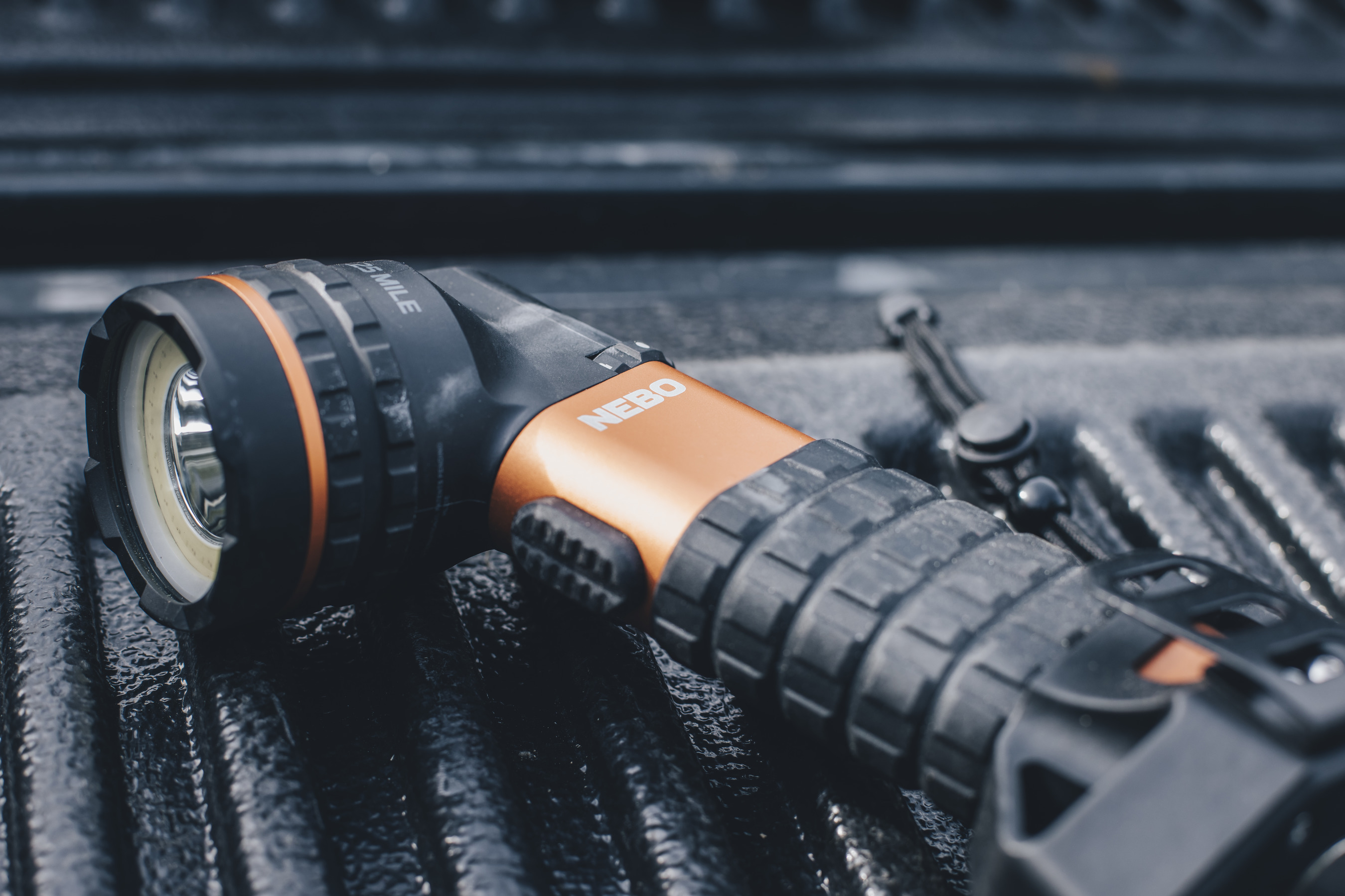 Eine schwarz-orange Taschenlampe auf strukturierter Oberfläche. Der Markenname 'NEBO' ist sichtbar.