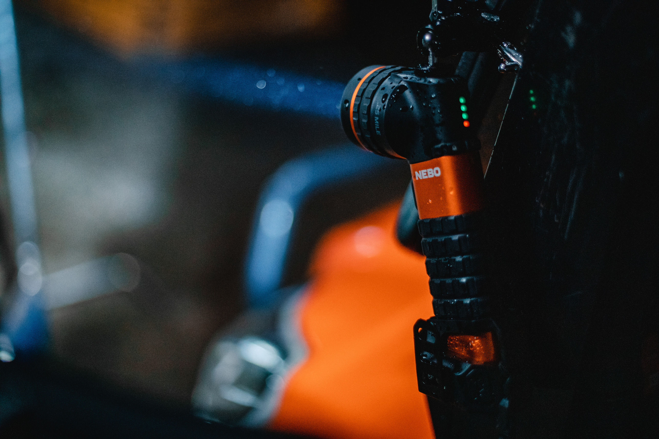 Nahaufnahme einer schwarz-orangenen Taschenlampe mit rotem Licht auf dunklem Hintergrund.