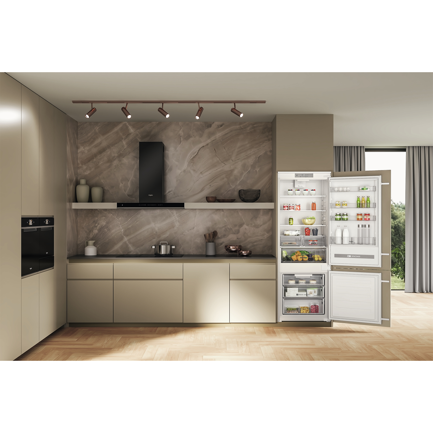 Cucina moderna con frigorifero aperto. Mobili beige e parete in pietra.