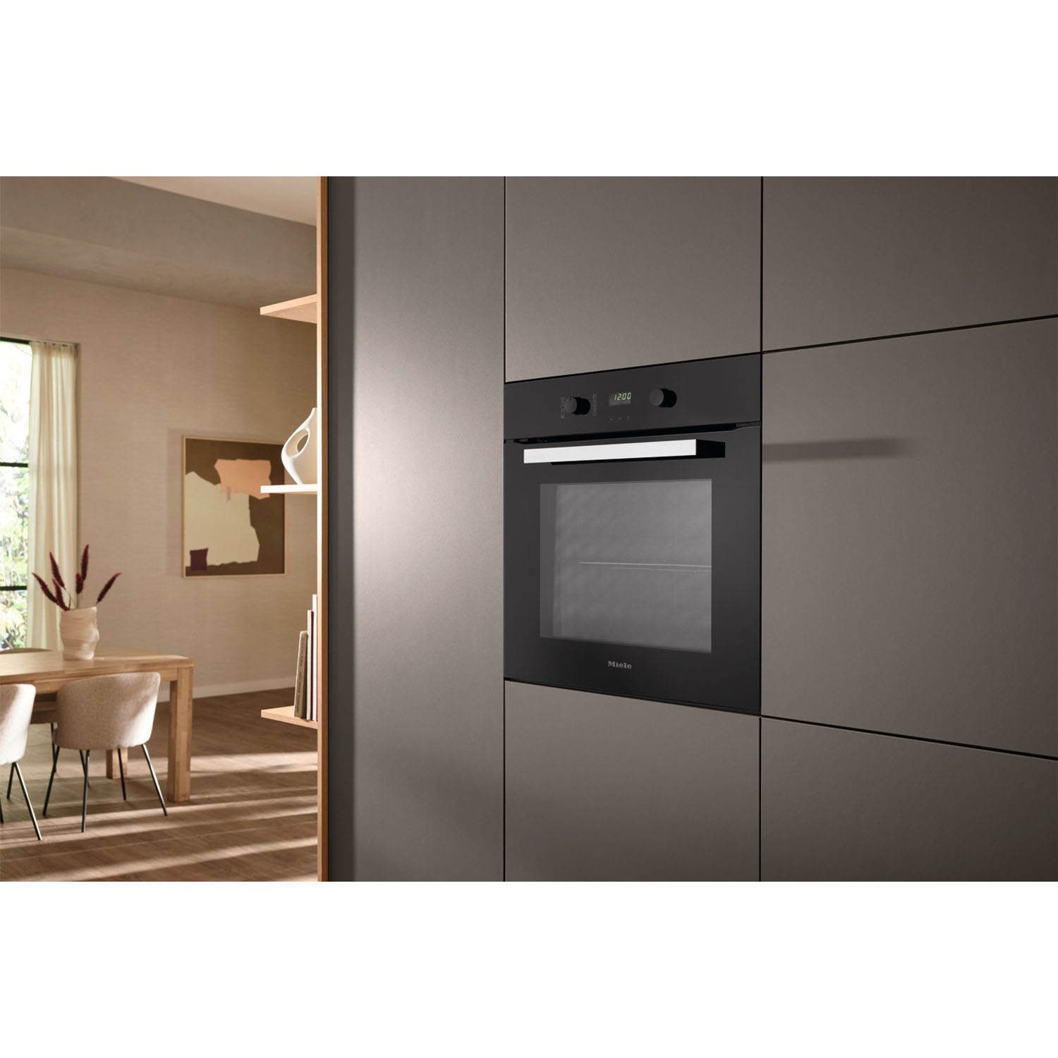 Forno nero a incasso in una cucina moderna. Armadi grigi e tavolo in legno con dipinto sullo sfondo.