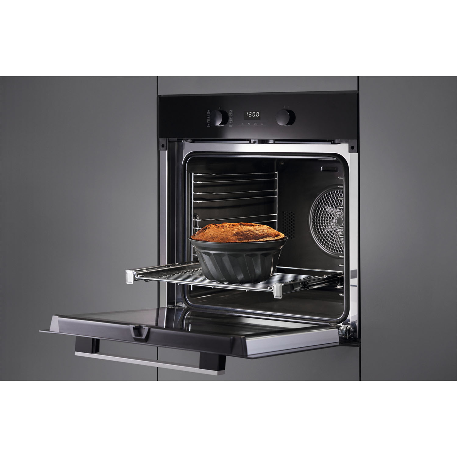 Un forno con la porta aperta e una torta all'interno su una griglia. Il forno è nero.