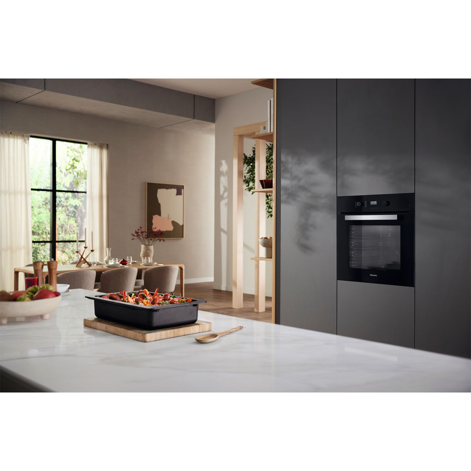 Cucina moderna con forno nero, tavolo da pranzo e piano di lavoro con cibo.