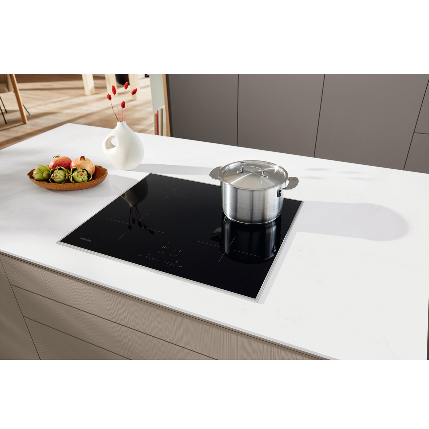Cucina moderna con piano cottura a induzione nero e pentola argentata sopra.