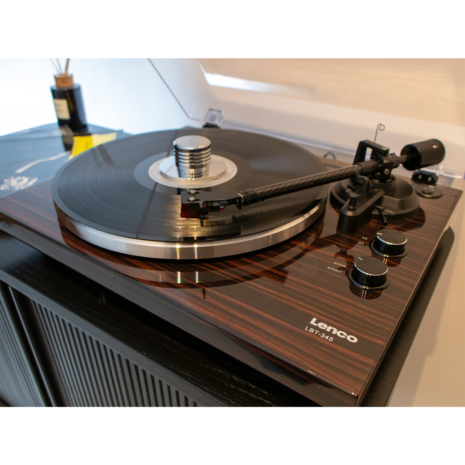 Un giradischi in legno con un disco in riproduzione e due manopole di controllo.