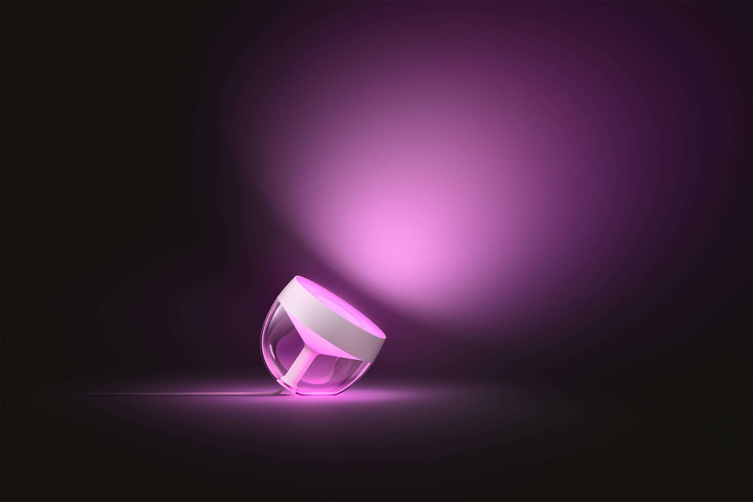 Ein rosa Licht mit weißem Sockel auf dunkler Oberfläche.