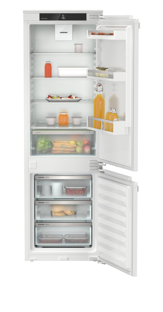 Weißer Kühlschrank mit offener Tür, gefüllt mit Essen. Glassregale, verschiedene Lebensmittel und Flaschen sind sichtbar.