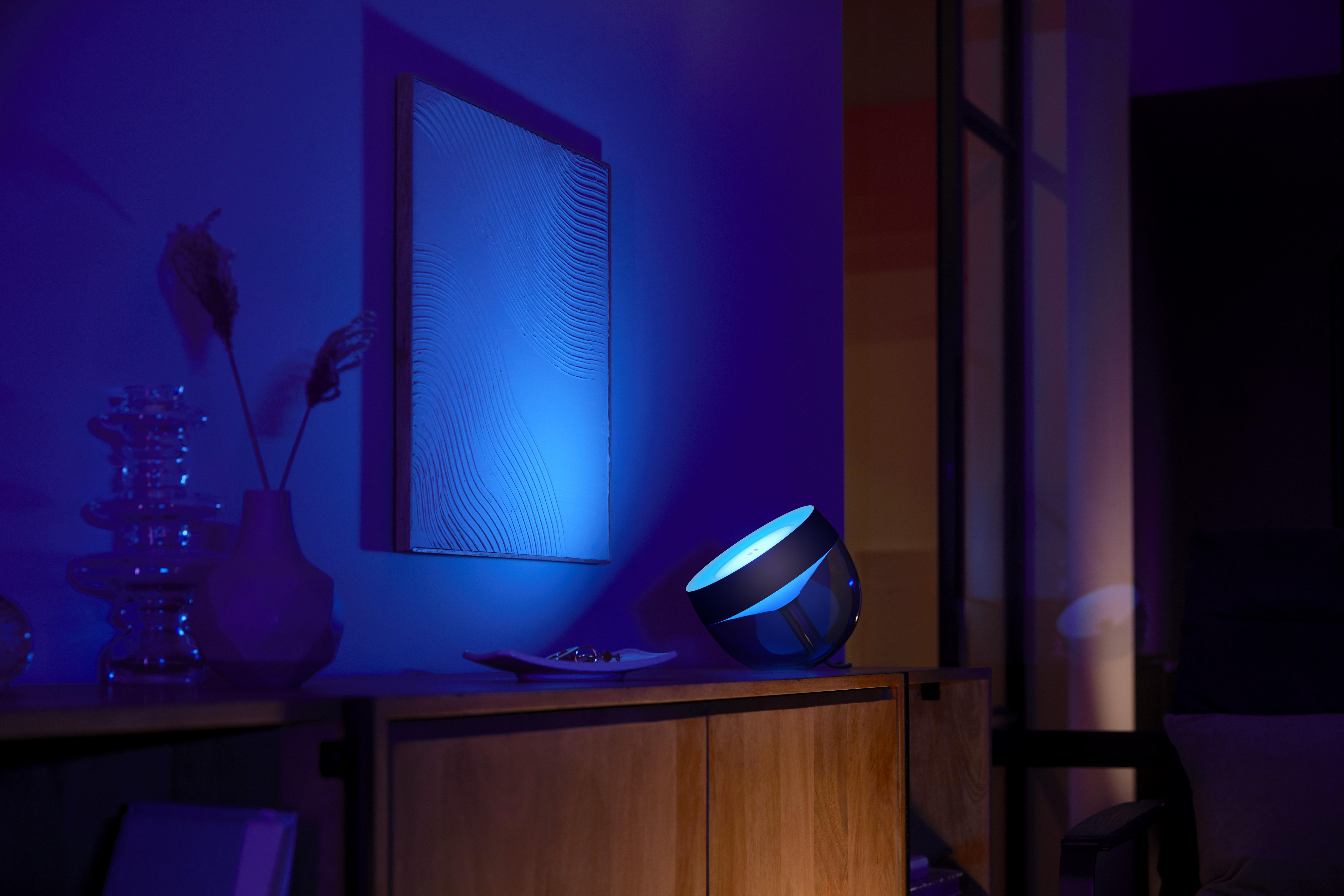 Ein Raum, der von blauem Licht beleuchtet wird. Eine Lampe und ein Gemälde sind zu sehen.