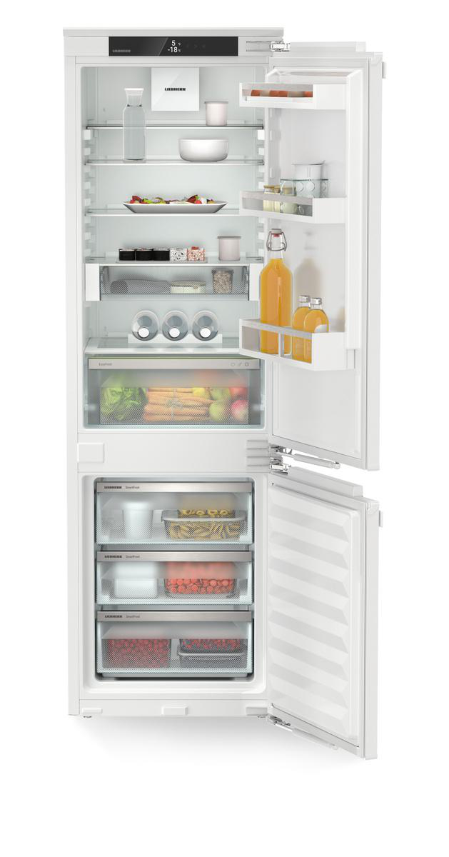 Ein weißer Kühlschrank ist geöffnet und zeigt Regale mit Lebensmitteln und ein Gefrierfach darunter.