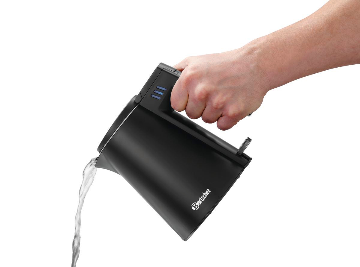 Hand gießt Wasser aus einem schwarzen Wasserkocher. Wasserstrahl und Wasserkocher sichtbar.