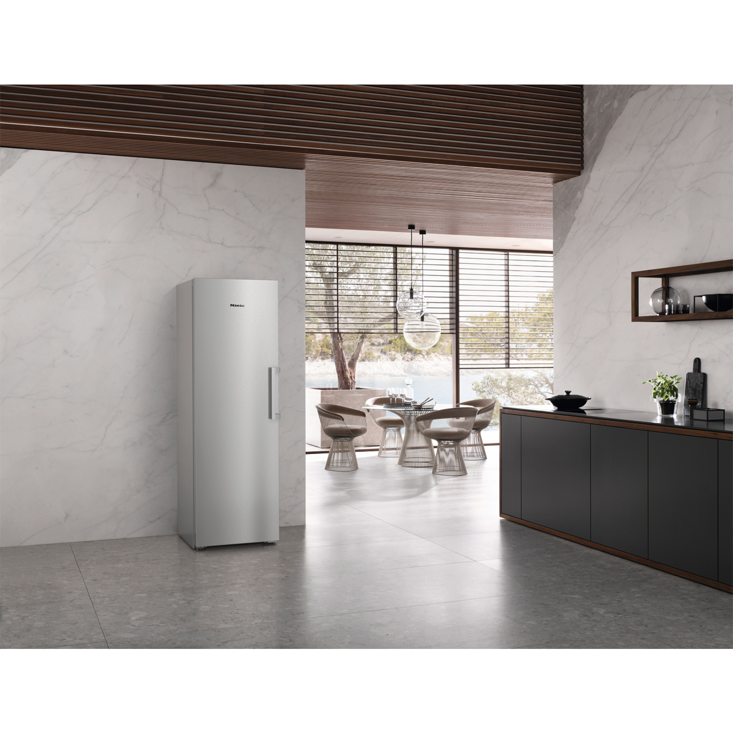 Frigorifero argentato in una cucina moderna. Mobili scuri, pareti in marmo e soffitto in legno.