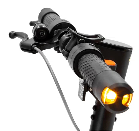 Zbliżenie kierownicy skutera z elementami sterowania, w tym dzwonkiem i światłami.