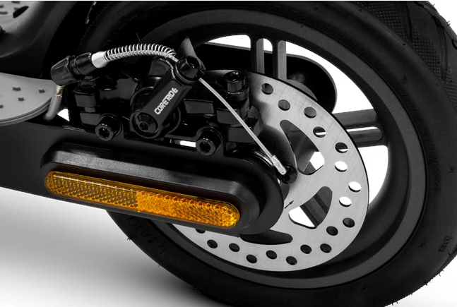 Zbliżenie tylnego koła skutera z hamulcem tarczowym i odblaskiem.