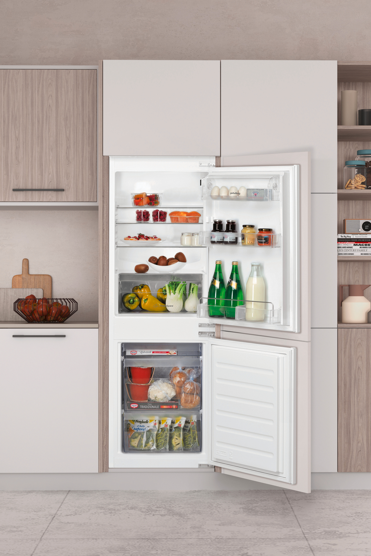 Ein offener Kühlschrank zeigt Obst, Eier, Gläser, Flaschen und Gemüse. Küchenschränke und Regale sind sichtbar.