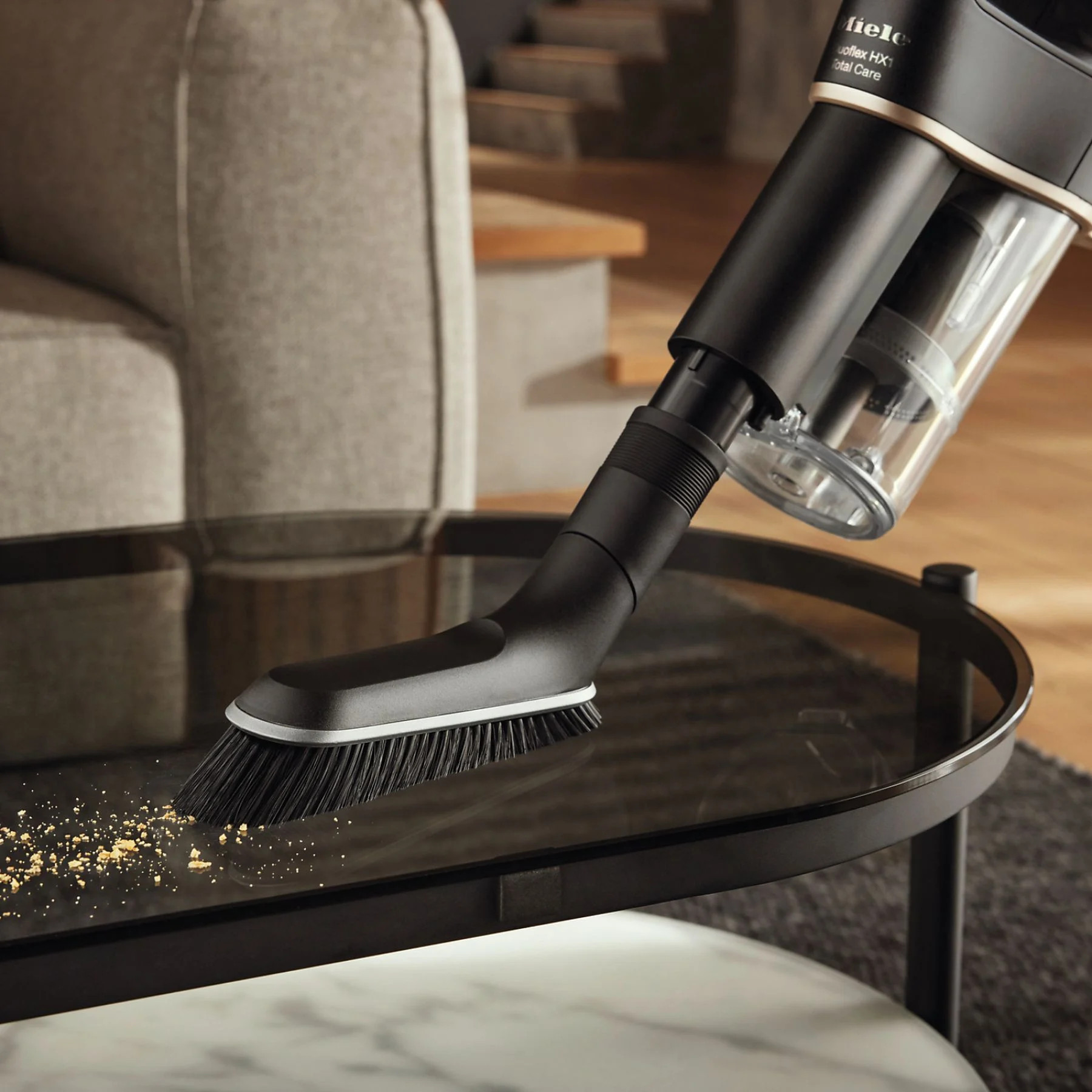 Czarny odkurzacz czyszczący szklany stół.