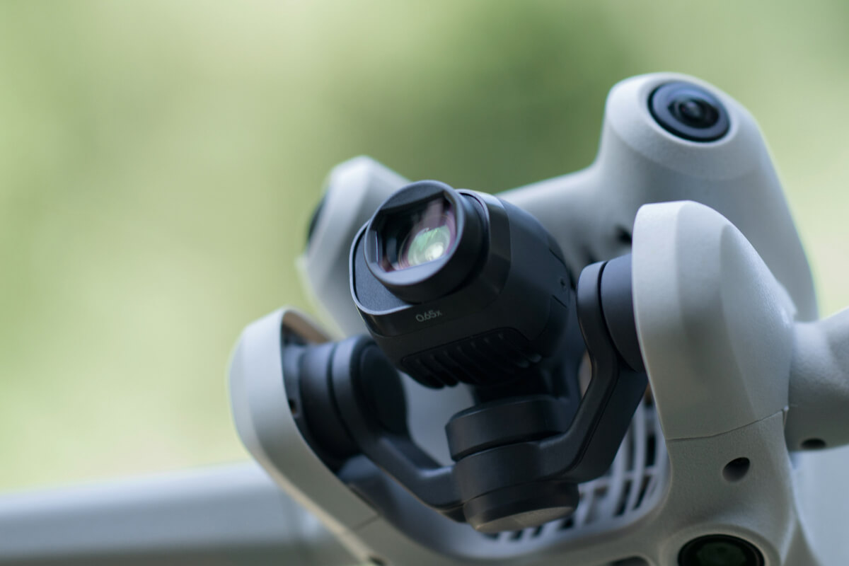 Zbliżenie kamery drona, z obiektywem i otaczającymi elementami. Rozmyte zielone tło.