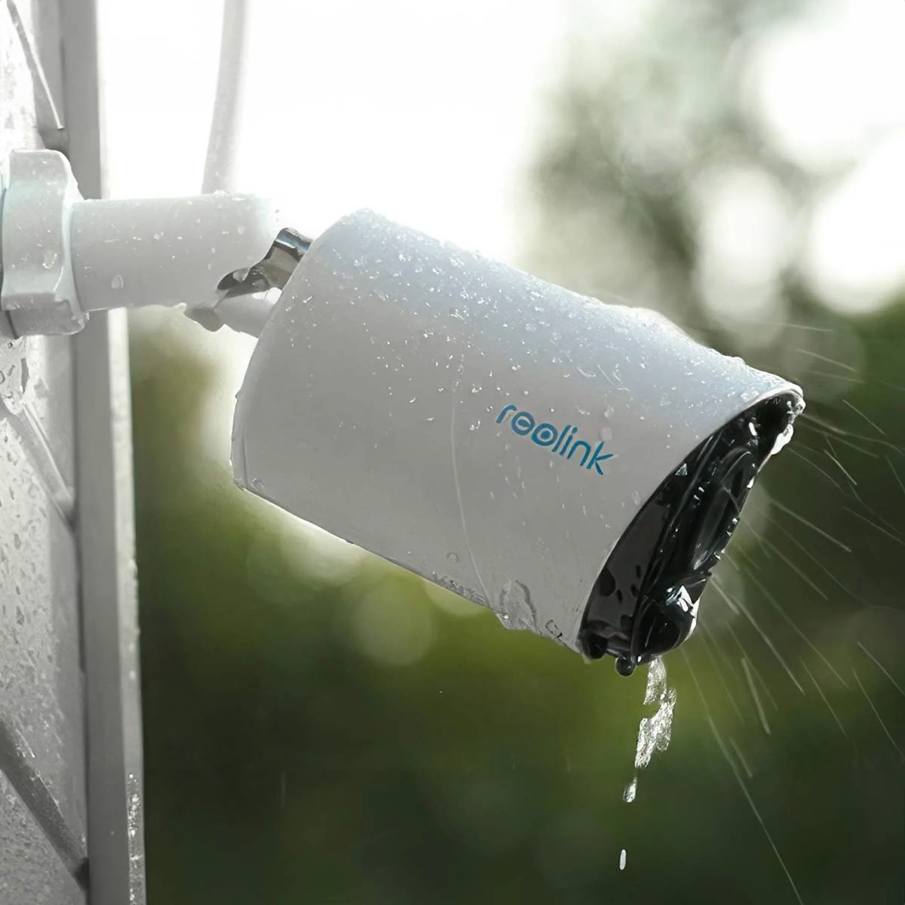 Eine weiße Reolink-Überwachungskamera an einer Wand befestigt. Wassertropfen sind sichtbar.