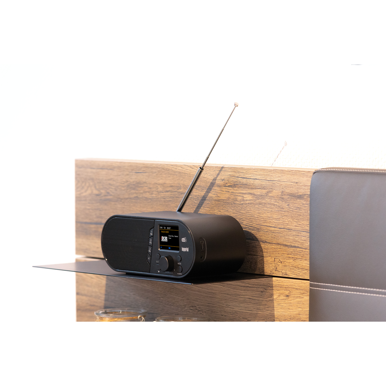 Zwarte radio op een plank. Houten panelen op de achtergrond. Een witte muur op de achtergrond.