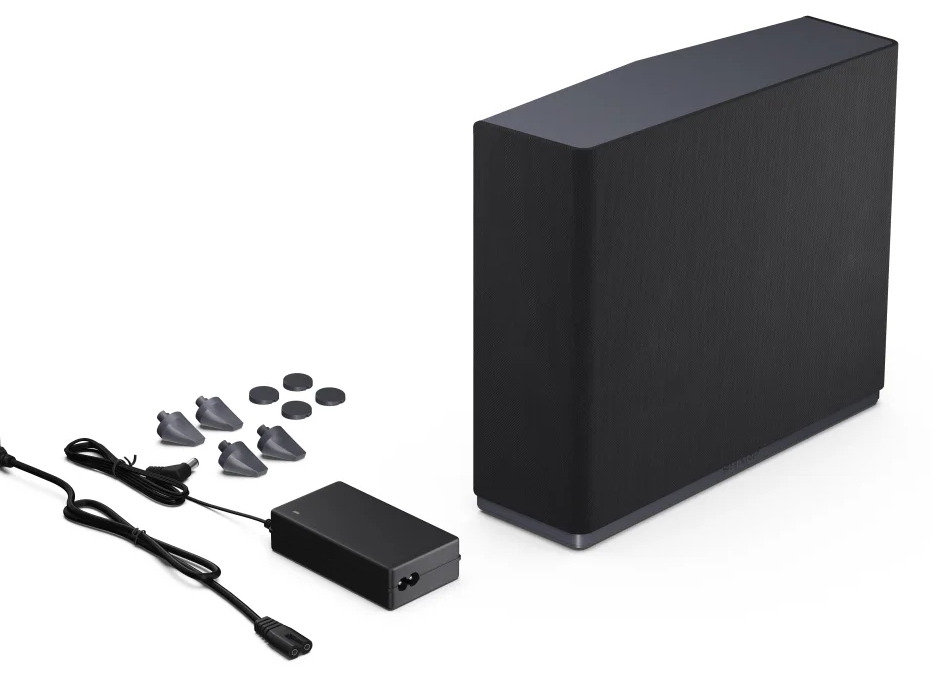 Czarny głośnik, zasilacz i akcesoria. Białe tło, minimalistyczna konfiguracja.