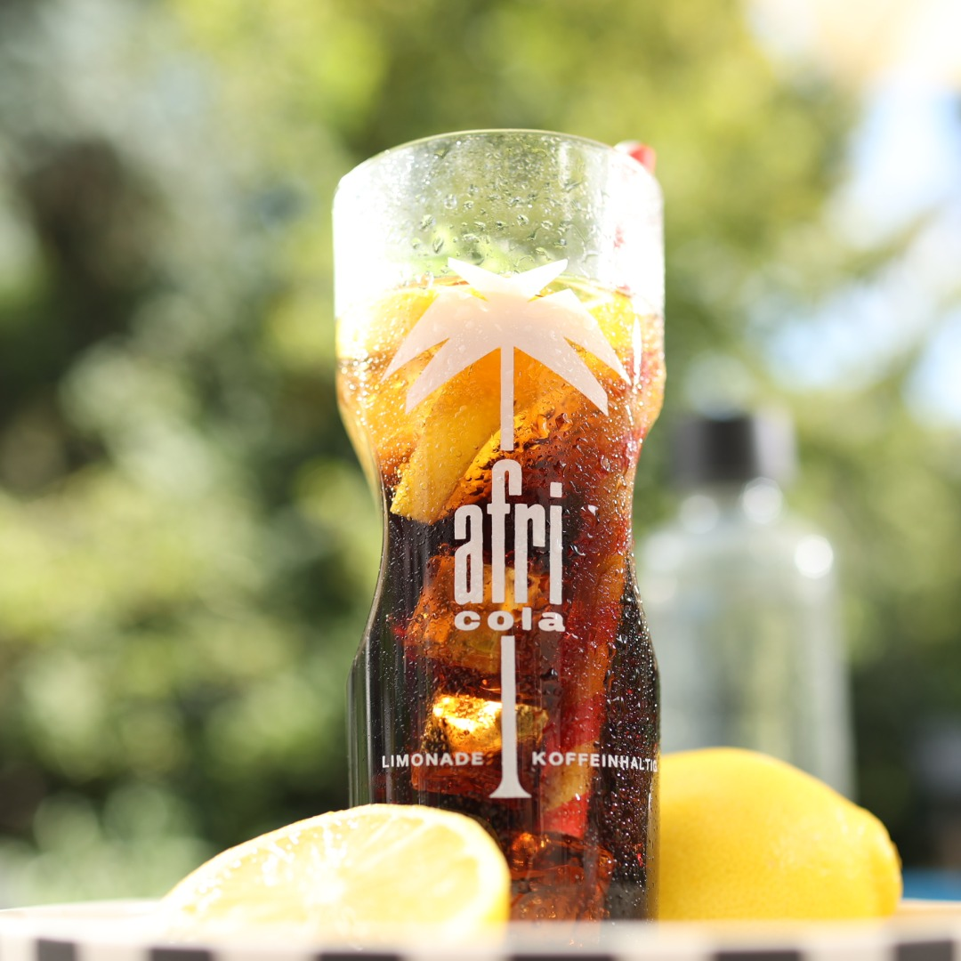 Glas Afri-Cola mit Zitronenscheiben und Eis.