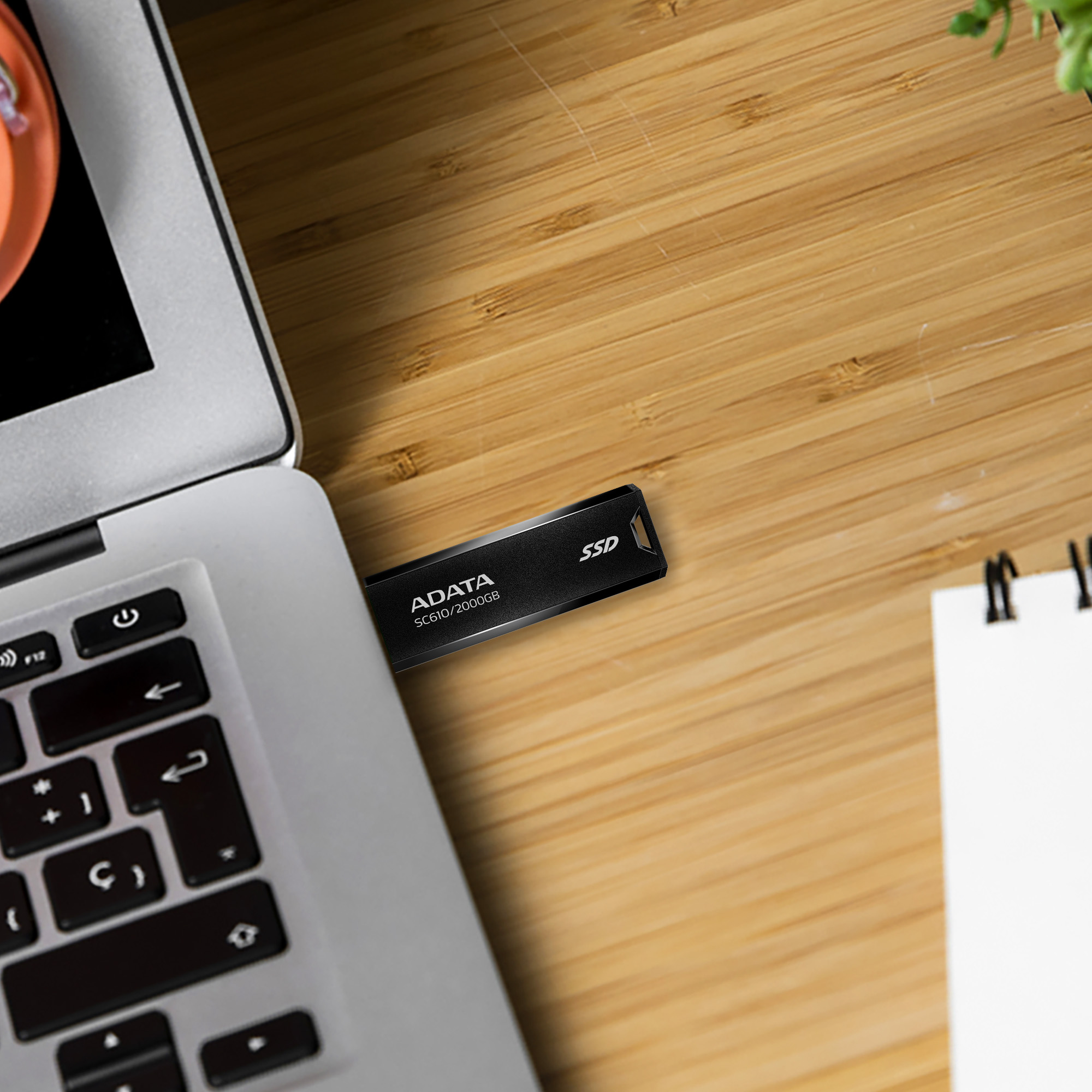 Egy laptop billentyűzete fekete SSD meghajtóval. Az SSD ADATA SC610/2000GB felirattal.