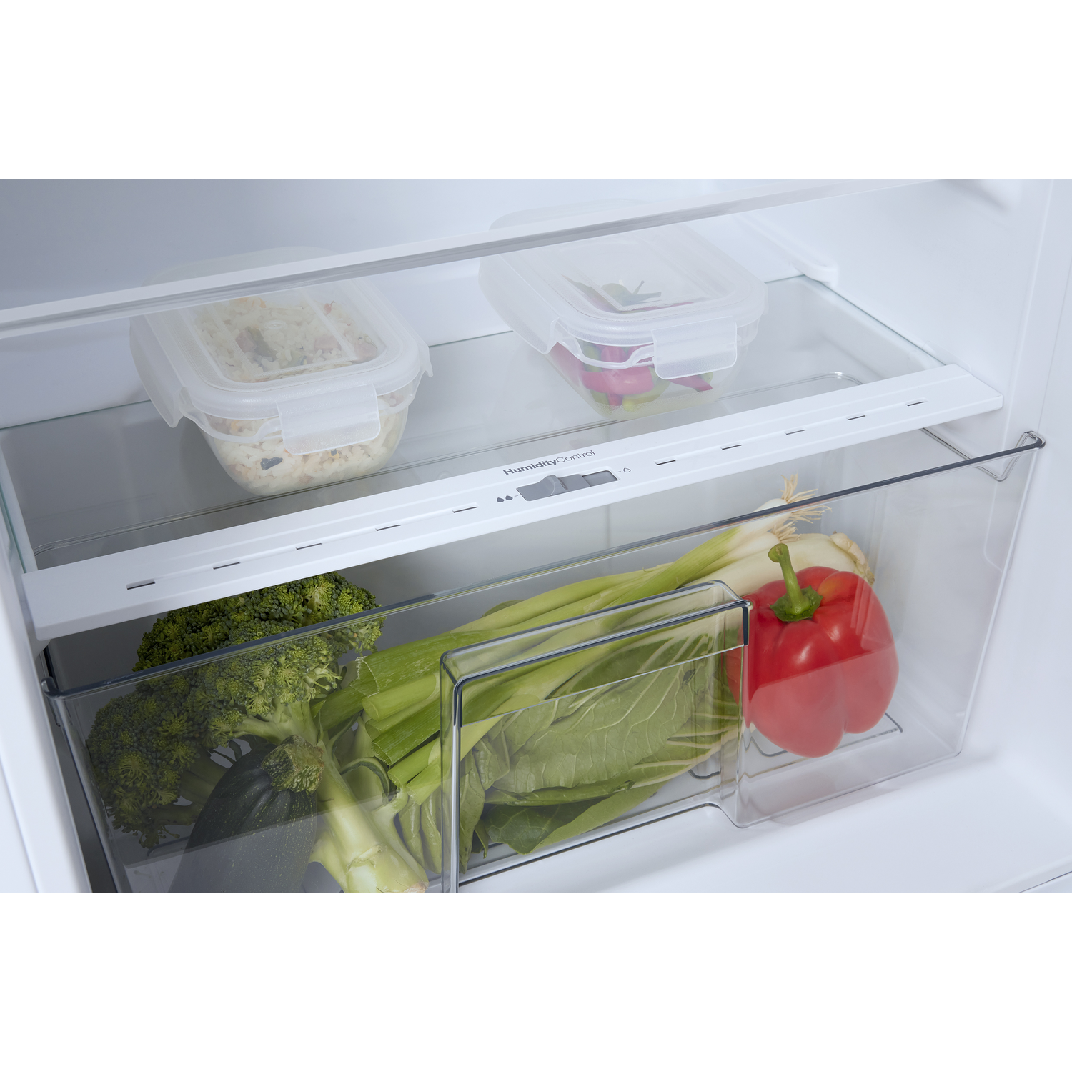 Inside a refrigerator drawer: vegetables, a container with food, and a glass shelf.