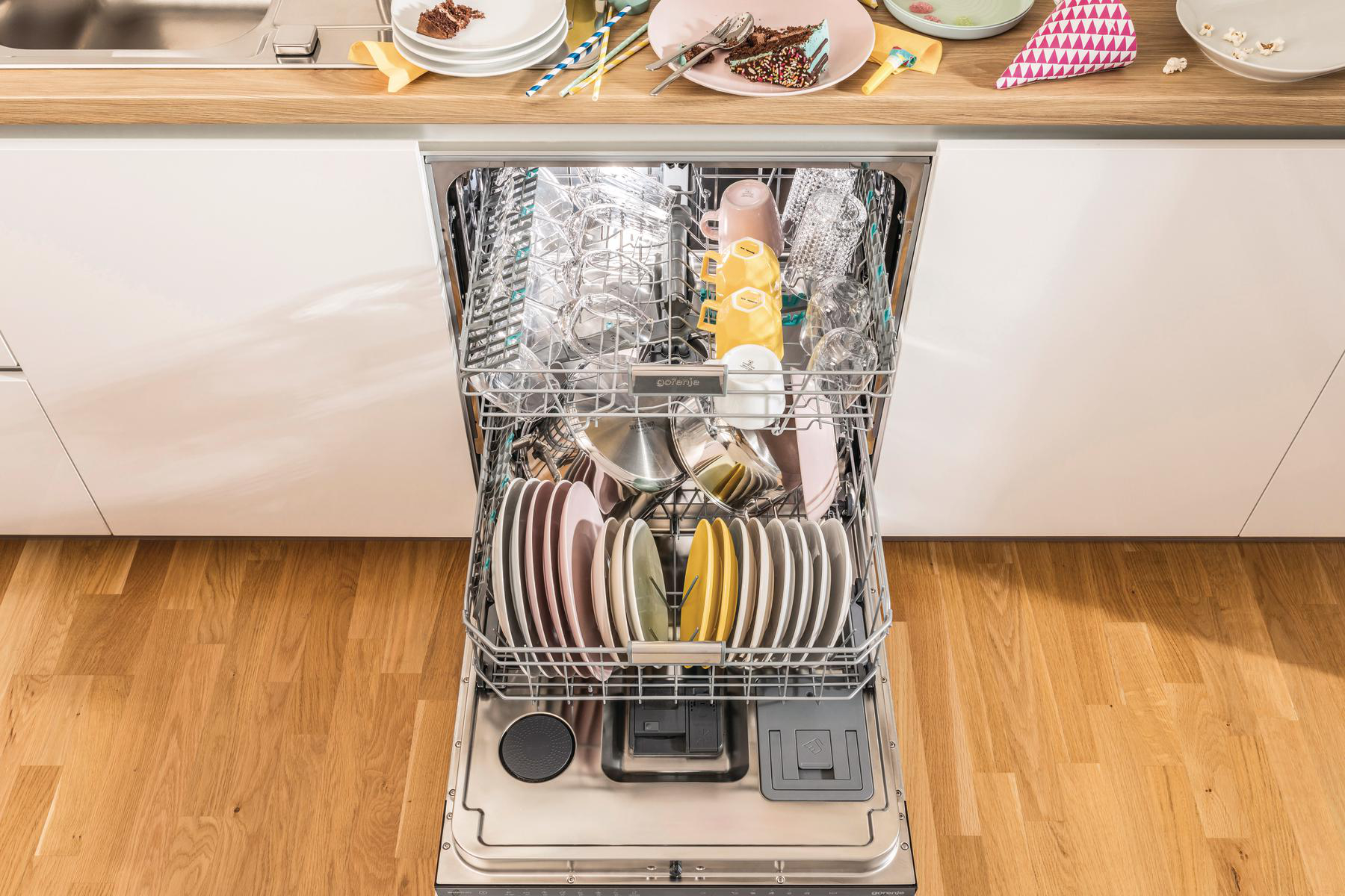Offener Geschirrspüler mit sauberem Geschirr und Besteck. Obere und untere Körbe sind sichtbar.