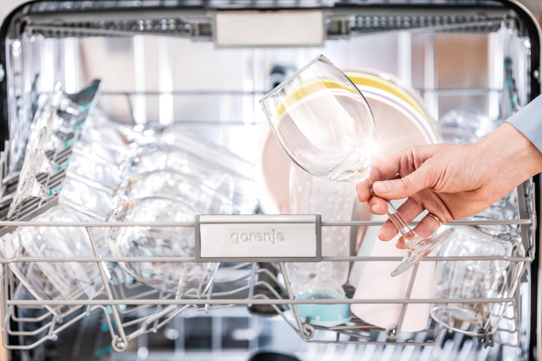 Eine Hand, die ein Glas in einem Geschirrspüler hält.