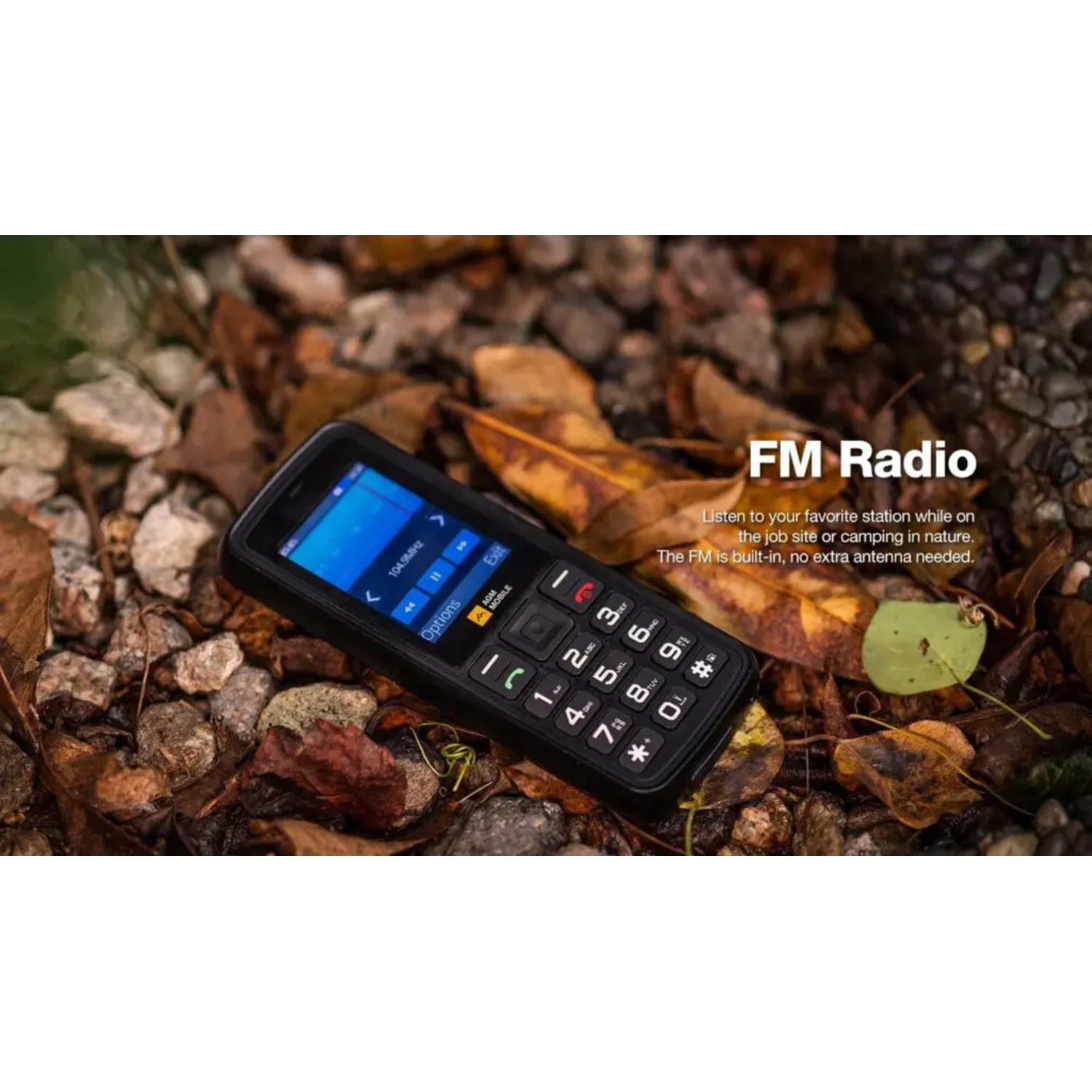 A rugged mobile phone with FM radio feature, lying on a bed of leaves and twigs.