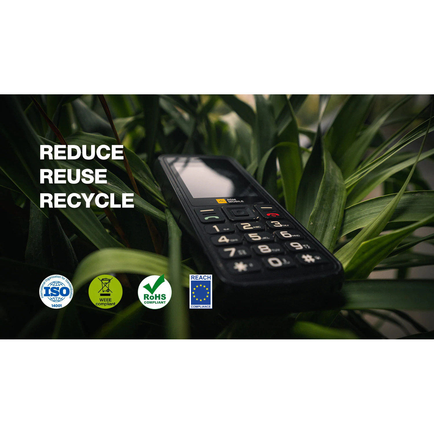 A black mobile phone with a keypad, lying among green leafy plants, with text: 'REDUCE REUSE RECYCLE'.