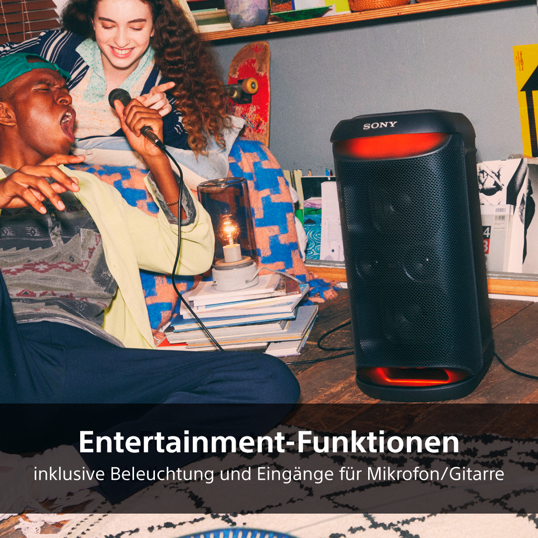 Leute singen und hören Musik von einem großen schwarzen Lautsprecher mit roten Akzenten.