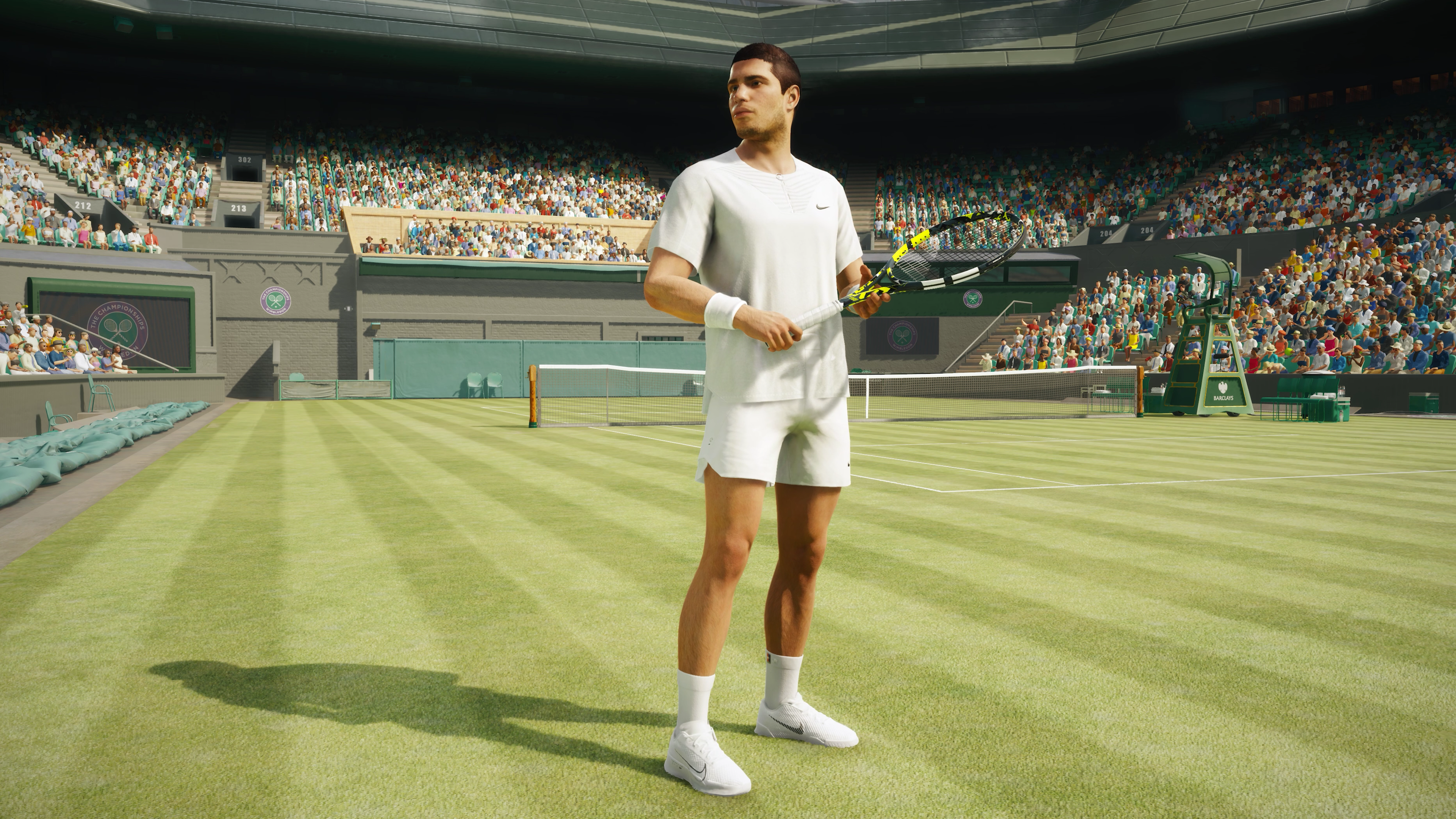 Tenisista stoi na korcie trawiastym, trzymając rakietę. Trybuny są pełne ludzi.