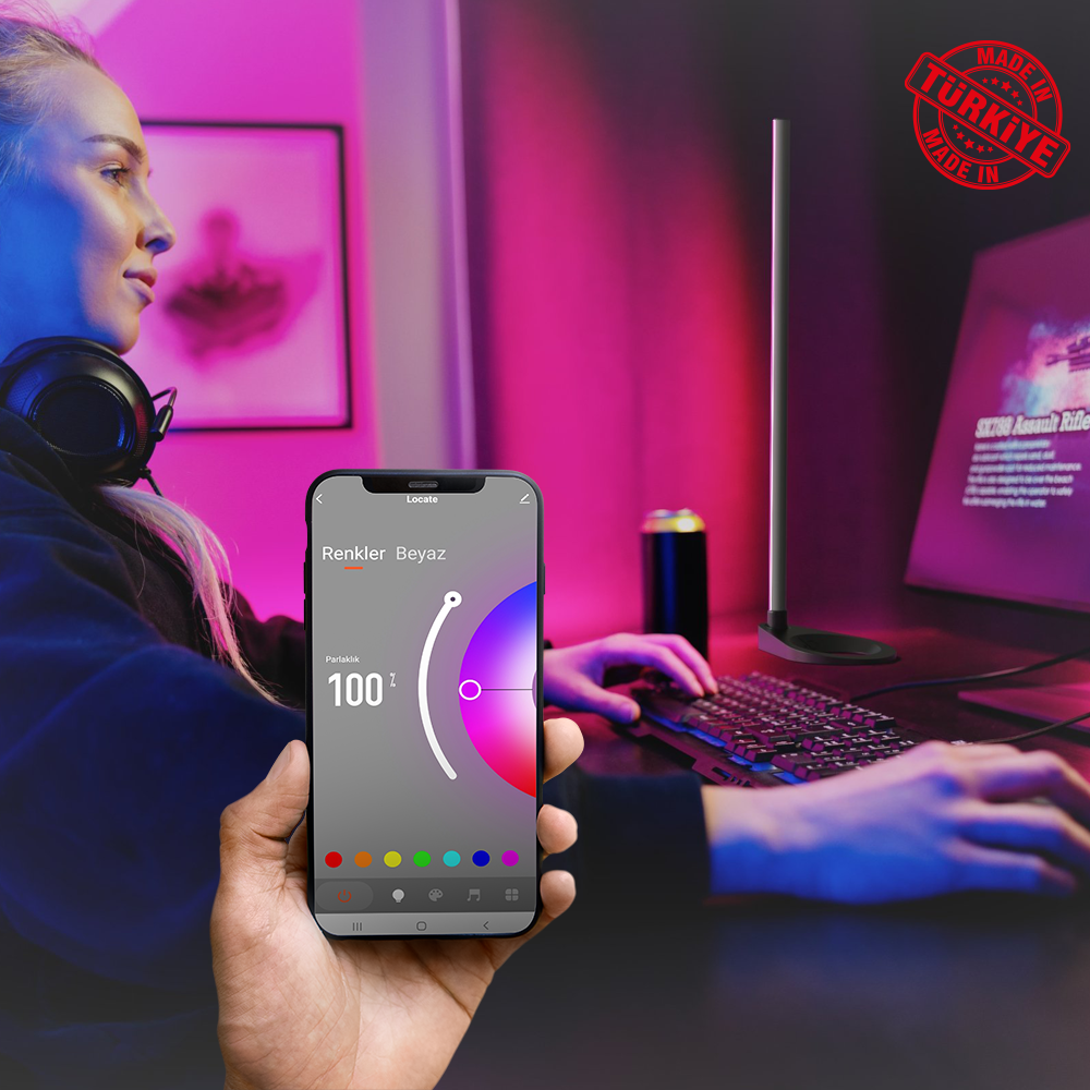 Kadın, arka planda bir monitör ve klavye ile bir ışığı kontrol etmek için telefon kullanıyor.